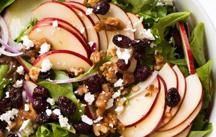 Overhead photo of Apple Salad with Candied Walnuts and Cranberries with vinaigrette dressing on the side