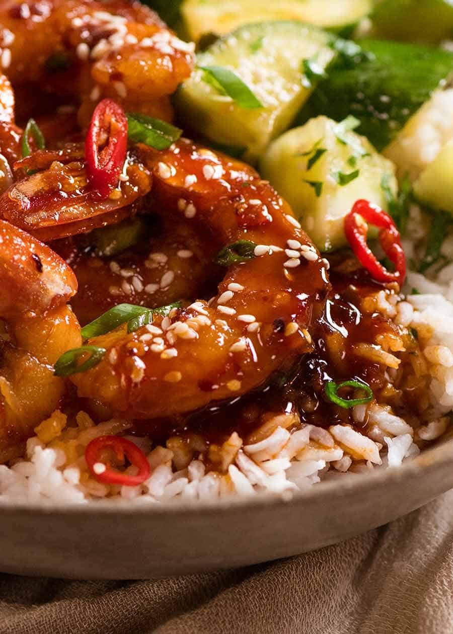 Close up of Asian Chilli Garlic Prawns served over rice with a quick Asian cucumber side salad