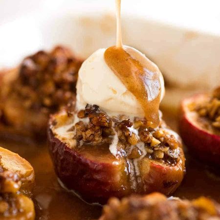 Close up of caramel sauce being drizzled over Baked Apples with ice cream on top in a baking dish, fresh out of the oven.