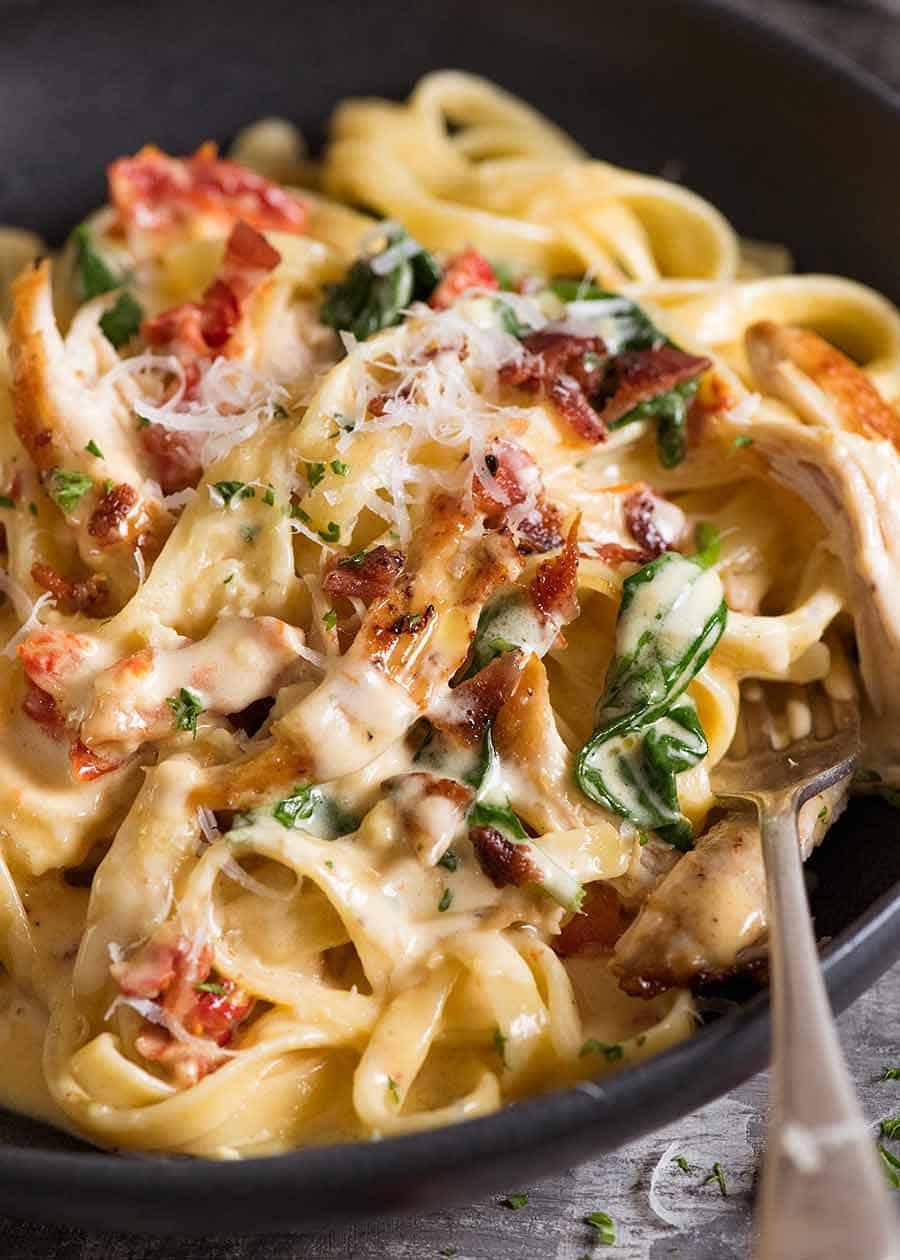 Close up of chicken pasta with creamy alfredo sauce, sun dried tomato, spinach and bacon