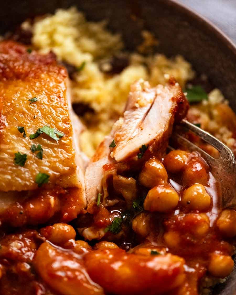 Close up of cut piece of Moroccan Chicken Tagine served on couscous