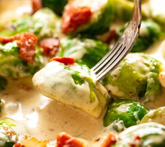 Fork picking up sautéed Brussels sprouts in a creamy sauce