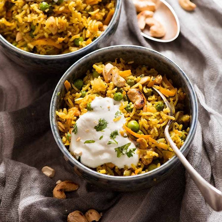 Two rustic bowls with Curried Rice made with Basmati Rice, topped with a dollop of yogurt