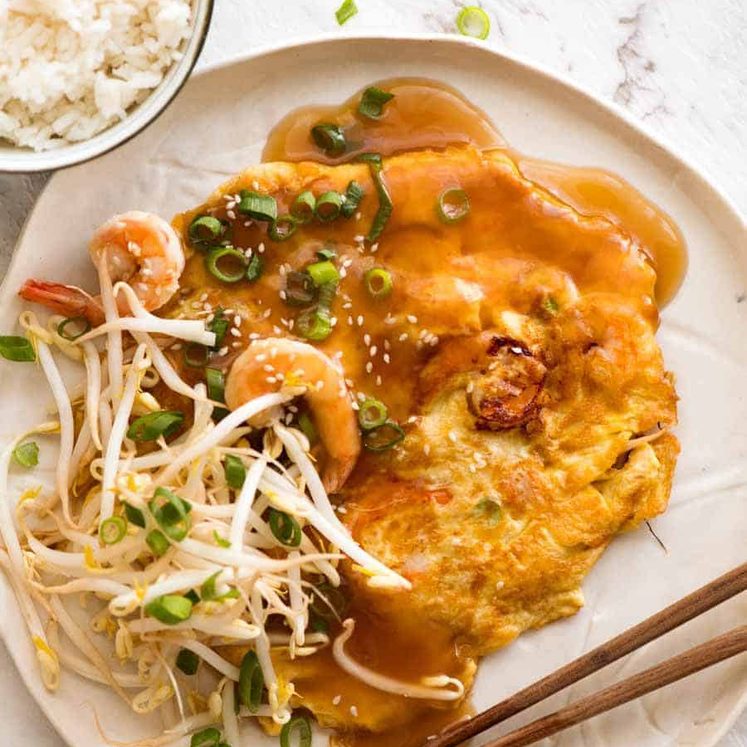 Overhead photo of Egg Foo Young on a rustic white plate with a side of rice, ready to be eaten