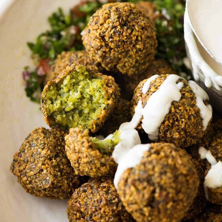 Close up of Falafels in a bowl drizzled with tahini sauce