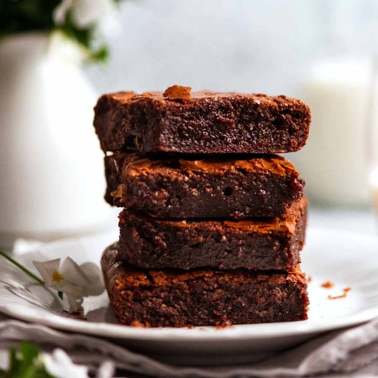 Stack of Flourless Chocolate Brownies (gluten free) slices with milk and flowers in the background