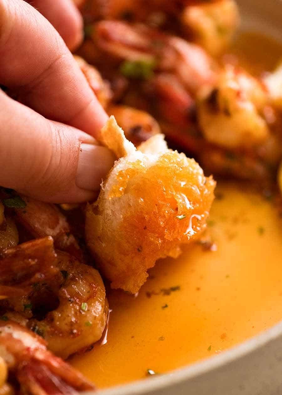 Dunking crusty bread into lemon garlic butter served with Garlic Prawns