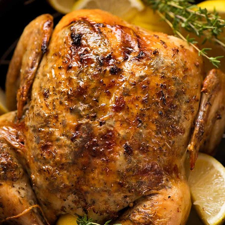 Overhead photo of Slow Cooker Roast Chicken (whole chicken) on a serving platter with lemon wedges and thyme, ready to be served