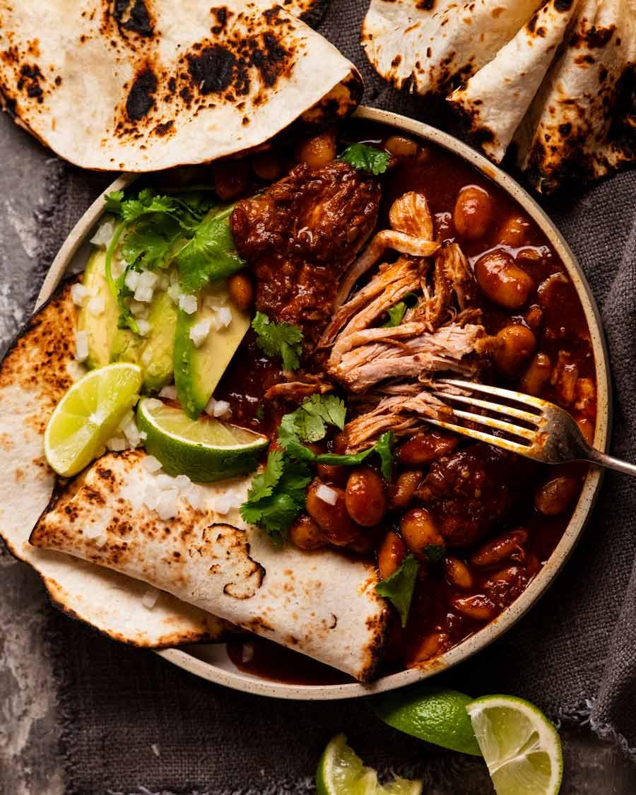 Mexican Chipotle Pork and Beans with tortillas, avocado and limes on the side