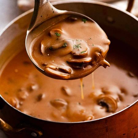 Ladle scooping up Mushroom Gravy from saucepan