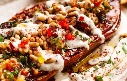 Roasted sweet potato steaks on a plate with whipped tahini yogurt sauce