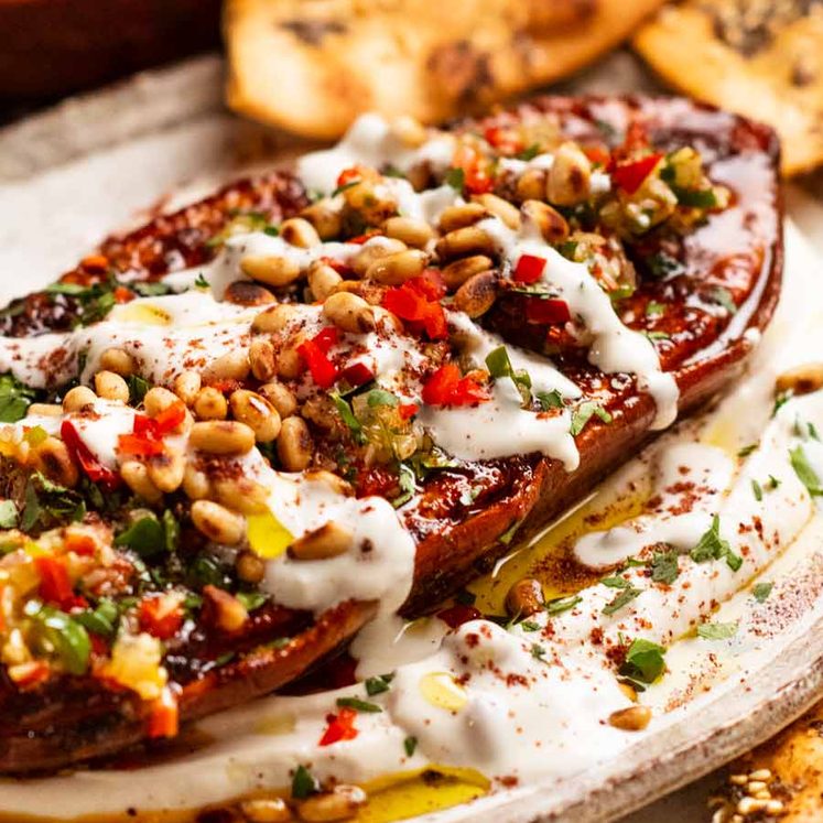 Roasted sweet potato steaks on a plate with whipped tahini yogurt sauce