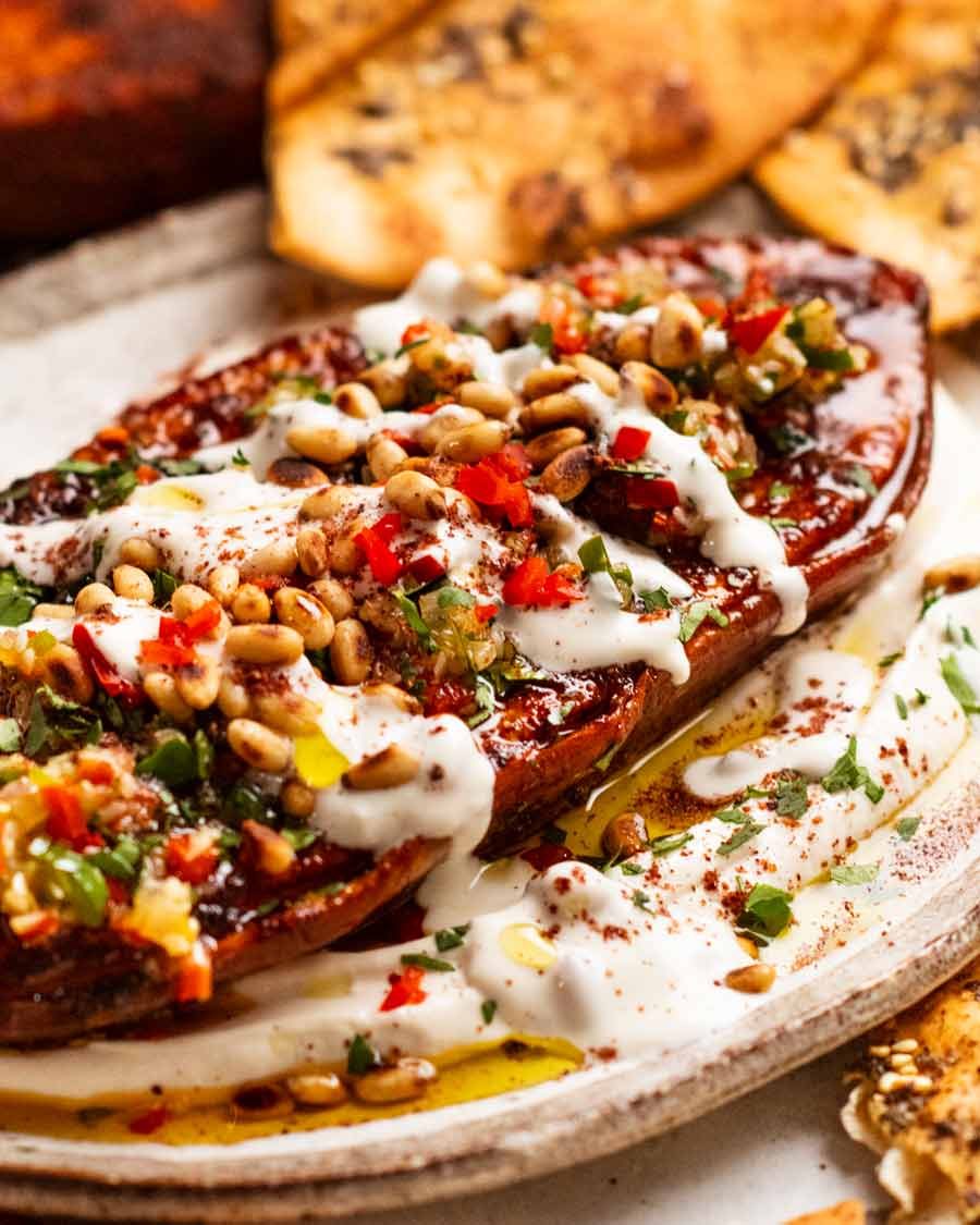 Roasted sweet potato steaks on a plate with whipped tahini yogurt sauce