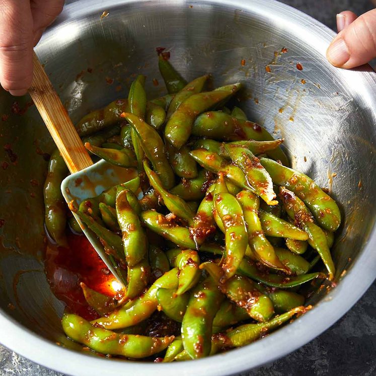 Tossing Spicy edamame in a bowl