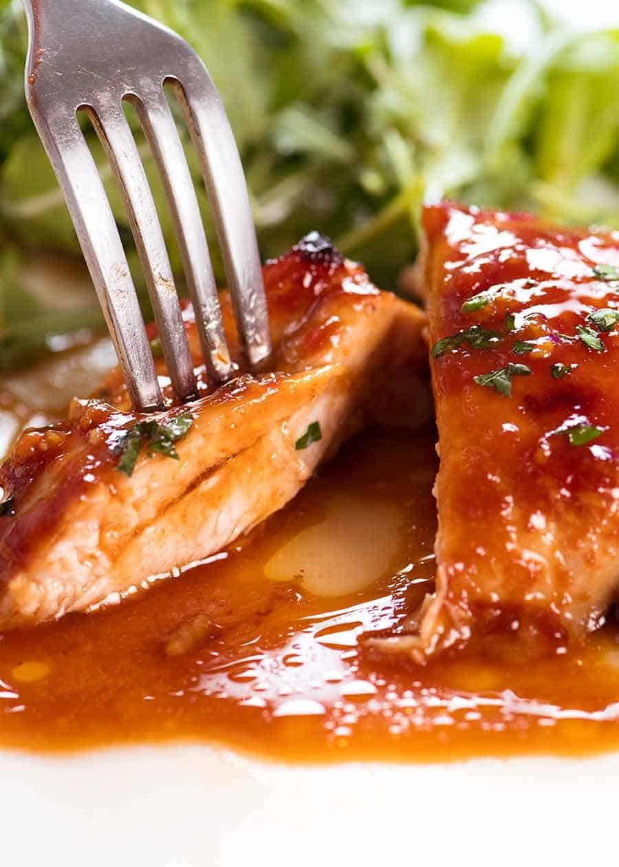 Close up of fork piercing a slice of Sticky Baked Chicken Thighs